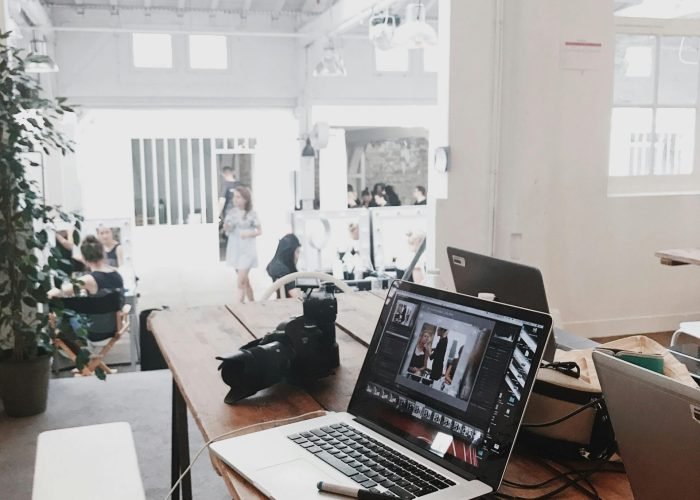 A bright, modern workspace featuring laptops, a camera, and a drawing tablet in an indoor office.